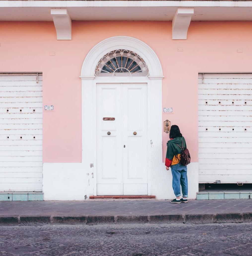 person-standing-front-pink-white-painted-building_web